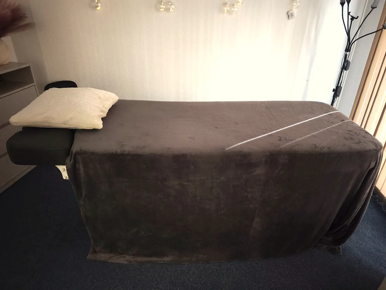 Massageliege mit Kissen und dunkler Decke